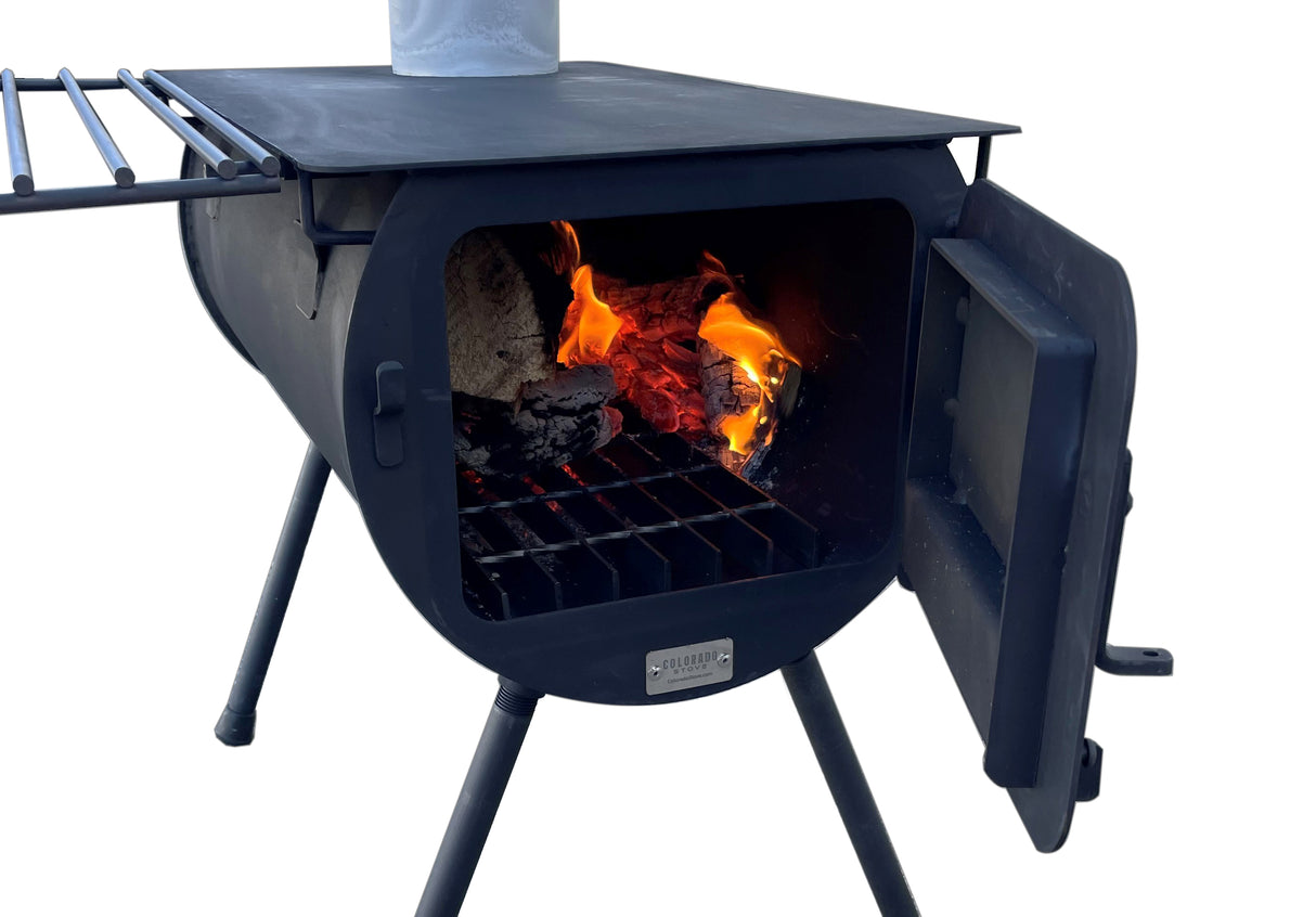 Black Colorado outdoor wood stove with fire, side shelf, and a metallic finish for heating and cooking.