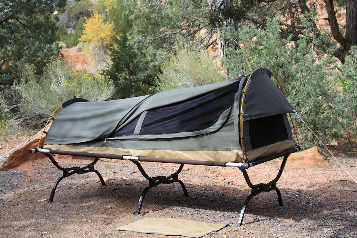 Green portable camping cot with protective canopy and mesh ventilation, designed for outdoor use.