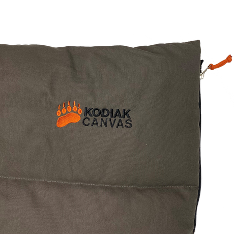 Kodiak Canvas sleeping bag in dark green with orange logo, durable, waterproof, perfect for camping.