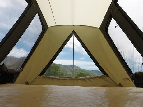 Interior view of a spacious tan camping tent with large windows showcasing a scenic mountain backdrop.