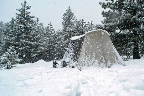 Winter camping tent in the snow, tan color, durable material, ideal for cold weather adventures.