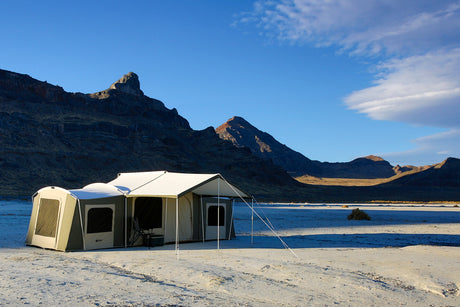 Spacious cream camping tent with a sunshade, set against a mountain backdrop, ideal for outdoor adventures.