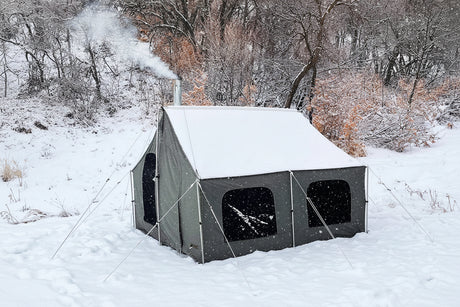 Outdoor winter tent, green canvas, durable material, snow-covered, equipped with a chimney for heating.