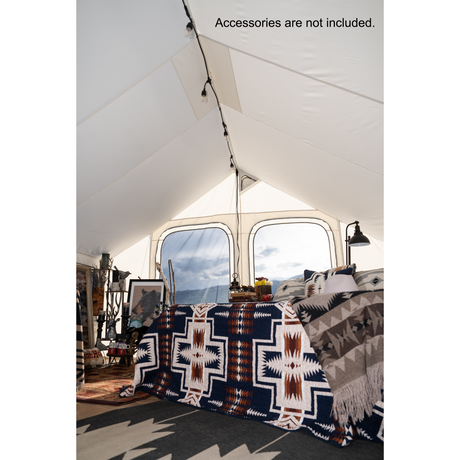 Glamping tent cozy interior featuring a patterned blanket in navy and white, perfect for glamping or camping.