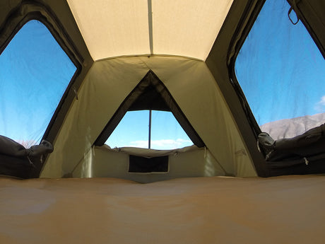 Interior view of a spacious green camping tent with three large windows and a light fabric roof.