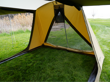 Spacious yellow camping tent interior with mesh window and grass flooring, ideal for outdoor adventures.