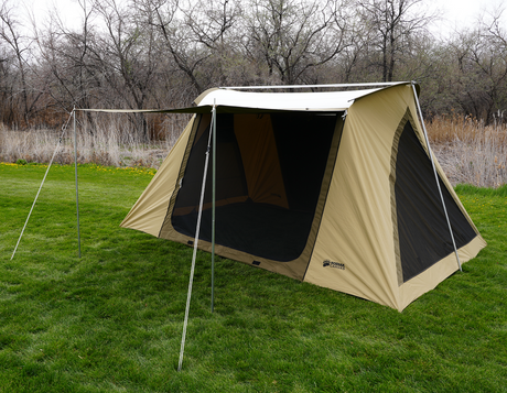 Spacious beige Kodiak Canvas tent with mesh windows, set up on grass for outdoor camping.